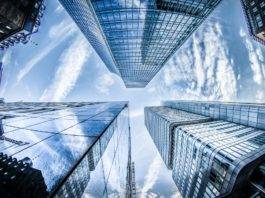 low angle photo of four high rise curtain wall buildings under white clouds and blue sky